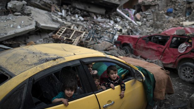 Children play inside a damaged car in a neighbourhood recently retaken by Iraqi forces.