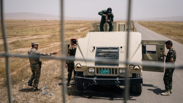 An Iraqi army soldier prepares to pour water over the engine of a Humvee after it overheated on the outskirts of Kabrouk in May.