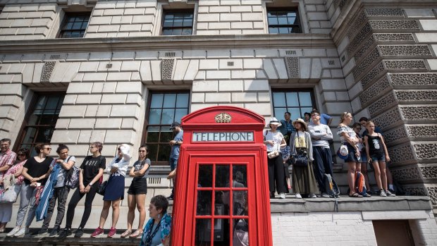 Tourists stand on a wall near a traditional red telephone box to try and catch a glimpse of Queen Elizabeth II on Wednesday.