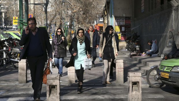 Pedestrians cross a street in central Tehran, Iran, on Saturday, ahead of crippling sanctions being lifted.