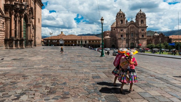 Two women wearing traditional clothes walking in the Plaza de Armas, in Cusco.