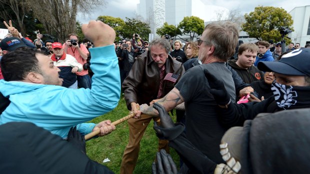 Anti-Trump protesters try to take a large piece of wood away from a Trump supporter at a rally for President Donald Trump at Martin Luther King Jr Civic Centre Park in Berkeley.