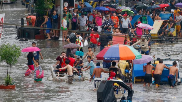 Residents wade through flood waters following overnight rains brought about by typhoon Talim inundated low-lying areas in Bacoor township, Manila, Philippines, on Tuesday.