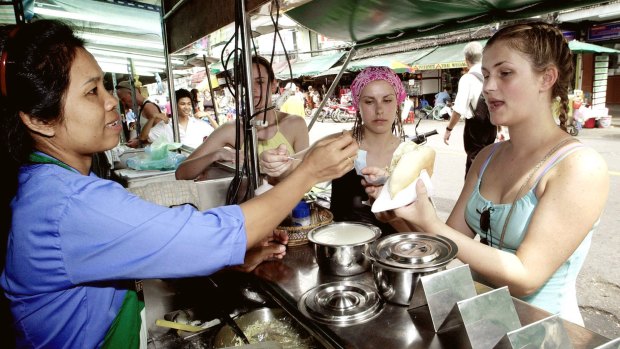 Tourists are served food from a street vendor on Khaosan Road.