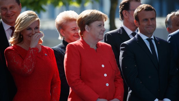 German Chancellor Angela Merkel, French President Emmanuel Macron and other leaders smile as President Trump speaks.