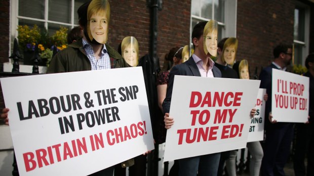 Conservative Party activists wearing Nicola Sturgeon masks protest ahead of a speech by Labour leader Ed Miliband.
