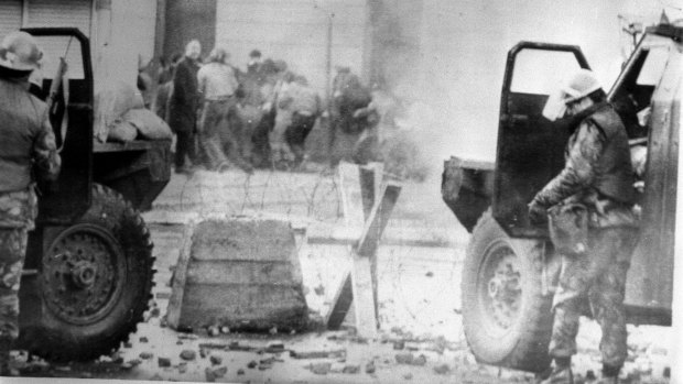 British soldiers taking cover behind their sandbagged armoured cars while dispersing rioters with CS gas in Londonderry, Northern Ireland on Bloody Sunday. 