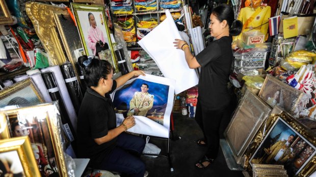 Vendors prepare portraits of Thai Crown Prince Vajiralongkorn for sale at a shop.