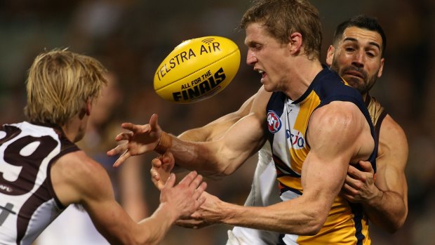 Scott Selwood of the Eagles is tackled by Will Langford and Paul Puopolo of the Hawks.