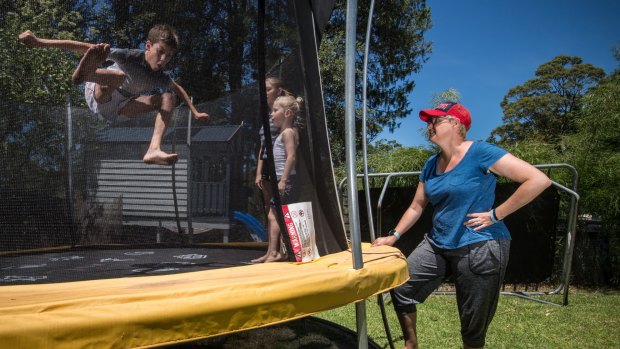 Dimity Statheos watches her children, Silas and Karis with neighbour Lydia, on their new trampoline with their old trampoline in the background. 