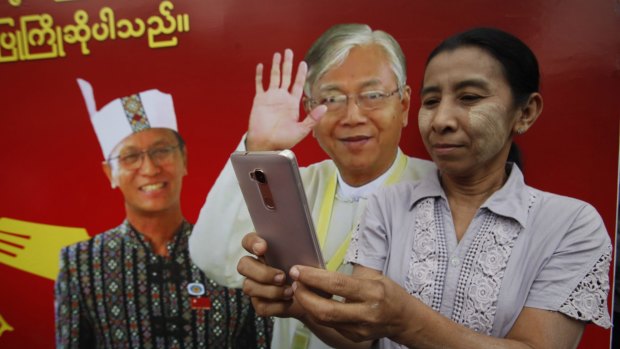A National League for Democracy supporter takes photos with a billboard featuring Myanmar's new president Htin Kyaw and vice president Henry Van Hti Yu, left, in Mandalay.