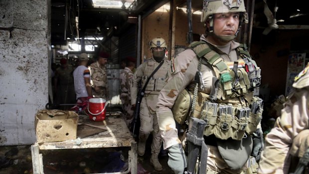 Security forces on duty at the site of a bomb explosion at an outdoor market in Baghdad's northern neighborhood of Shaab on Tuesday. 