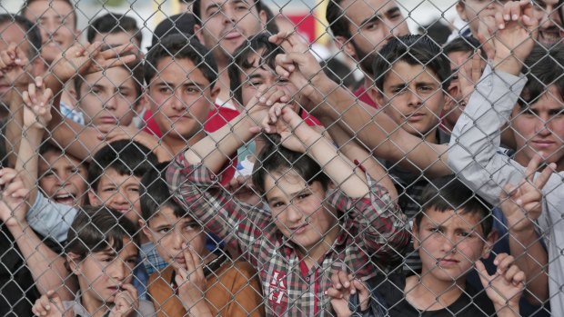 Migrants stand behind a fence at the Nizip refugee camp in Gaziantep, south-eastern Turkey.