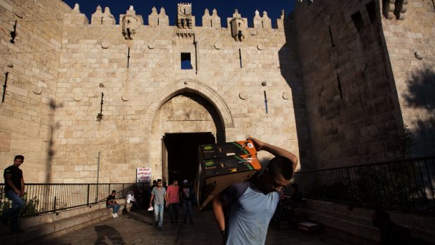 Palestinians walk past Damascus Gate in Jerusalem on Sunday, a few hours after an 18-year-old Palestinian stabbed an Israeli border policeman.