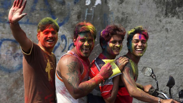 Young men with their faces smeared with coloured powder as they ride a motorbike during Holi festivities in Mumbai.