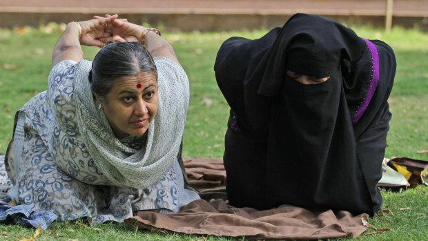 Trainer Chandrikaben Kansara, left, teaches yoga to a Muslim woman in a garden in Ahmedabad, India.