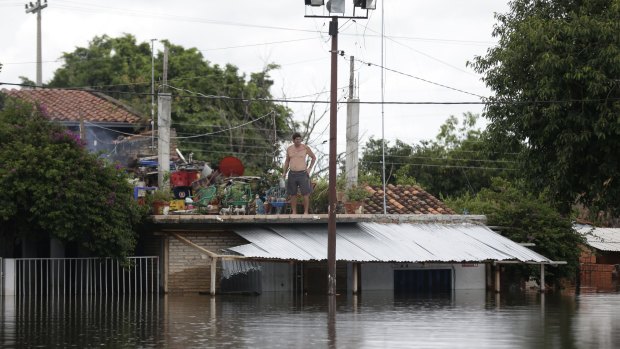 A man observes the water from the roof of his home in a flooded neighborhood in Asuncion, Paraguay, on Sunday.