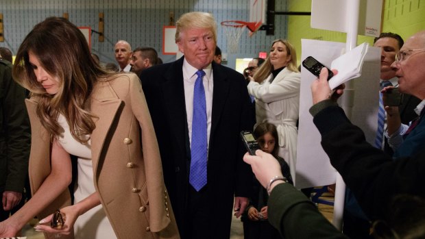 Republican presidential candidate Donald Trump, accompanied by his wife Melania, talks with reporters as he waits in line to vote.