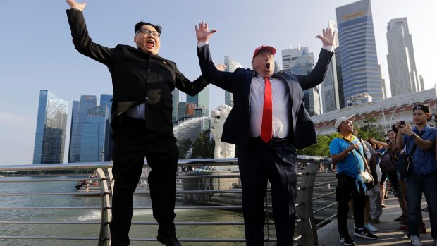 Kim Jong Un and Donald Trump impersonators, Howard X, left, and Dennis Alan, jump together as they pose for photographs at Merlion Park.