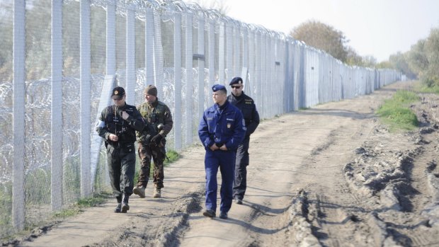 A Slovakian policeman, left, a Hungarian police officer, right, a Hungarian soldier, second left, and a Czech policeman patrol along the temporary border fence on the Hungarian-Serbian border near Roszke.