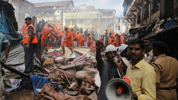 A rescue worker makes an announcement on a loudspeaker at the site of the building collapse in Mumbai.