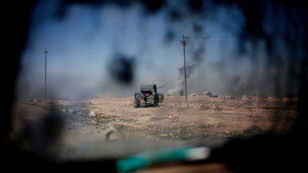 Iraqi police forces fire from a humvee at Islamic State positions from a hillside near Mosul on Monday.