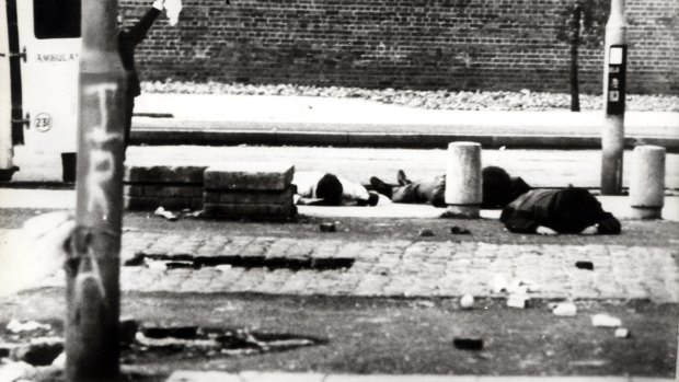 Behind a lamppost with IRA chalked on it a priest waves a white flag as ambulancemen dive for cover.  When the firing stops, they will bring in the wounded.

Wire Pic Associated Newspaper.  sent 31/01/72