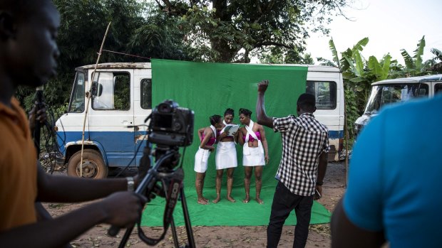 Actresses check the script before filming a Nollywood movie scene against a green-screen held up by bamboo poles and a rope, in the village of Illah, Nigeria.