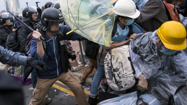 Battlefield: A police officer uses a baton on pro-democracy protesters near the office of the Chief Executive in Hong Kong.