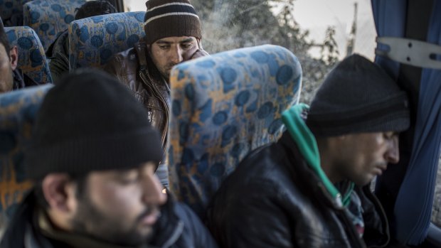 Guarded by police, Afghan and Kosovar Albanians caught entering the European Union illegally wait to be taken to a holding location, in Assothalom, Hungary.