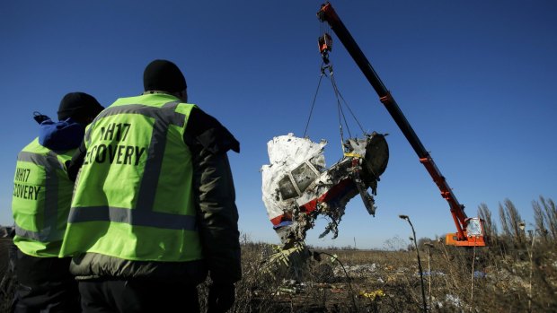 Investigators watch as a piece of wreckage from the Malaysia Airlines flight MH17 is recovered near the village of Grabovo in the Donetsk region of eastern Ukraine.