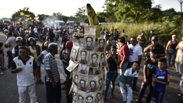 Banana republic: Demonstrators gather around a makeshift totem made of 100-bolivar banknotes during a protest in El Pinal, near Venezuela's border with Colombia.
