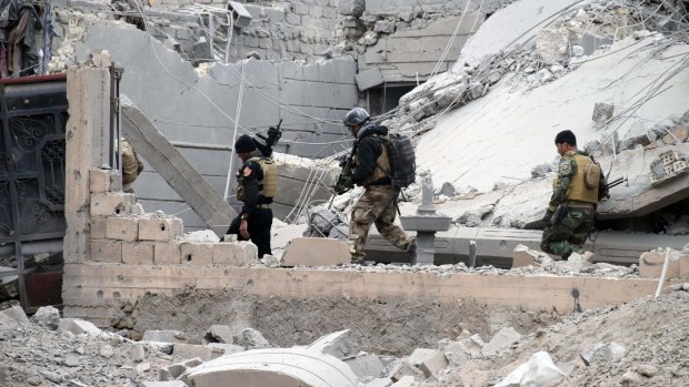 Iraqi security forces advance through damaged buildings towards central Ramadi this week.