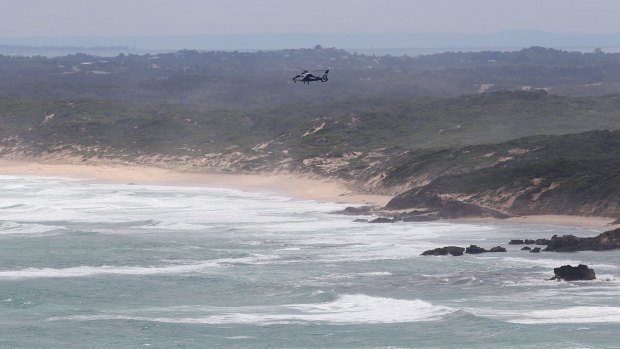 A search and rescue helicopter hovers over where two men went missing in waters off Cape Schanck on March 7. 