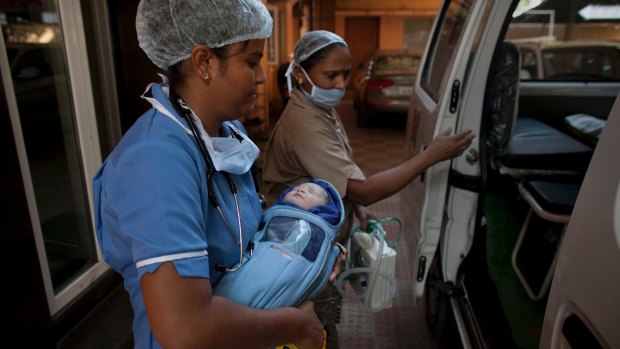 A newborn baby is transferred to an ambulance at surrogacy clinic in Anand, India, last year.