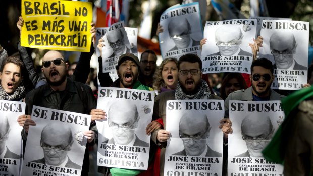 People protest with signs that read in Spanish "Wanted, Jose Serra, Foreign Minister, impostor of Brazil," and "Brazil isn't a democracy any more" as they wait for Serra outside the Foreign Relations Ministry in Buenos Aires, on Monday.