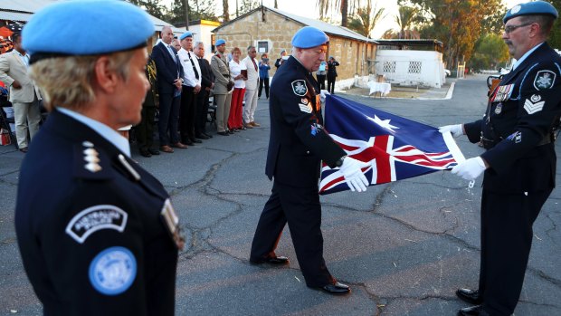 Australian UN police officers fold the Australian flag during a flag-lowering ceremony to end Australia's peacekeeping contribution in Cyprus on Friday.