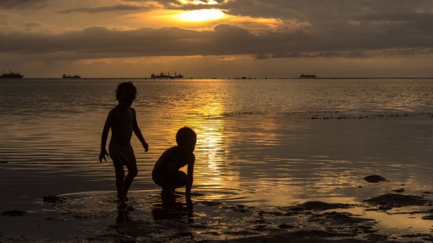 Children look for food on the beach at low tide in Dili, East Timor.