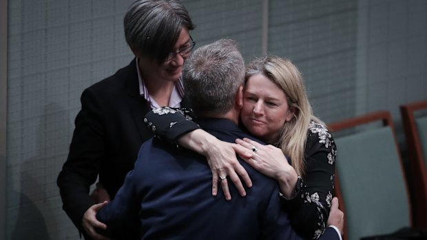 Opposition Leader Bill Shorten embraces Leader of the Opposition in the Senate Penny Wong and Senator Louise Pratt after speaking on Monday.