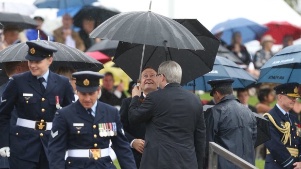 Bill Shorten and Kevin Rudd share an umbrella as they wait for the Prince of Wales and the Duchess of Cornwall to arrive at the Remembrance Day ceremony at the National War Memorial.