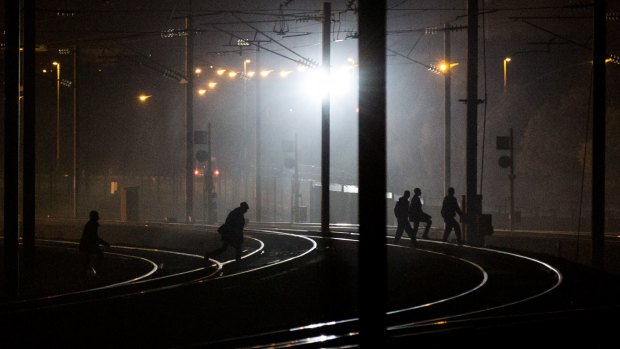 People walk across train tracks near the Eurotunnel terminal in Coquelles, Calais on Monday.