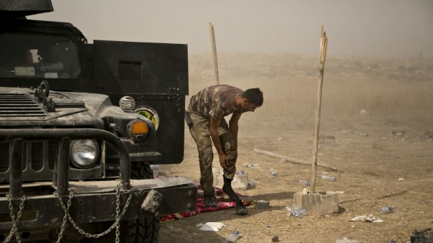 A soldier with Iraq's elite counterterrorism forces dresses next to his vehicle on the front line in Fallujah, Iraq, on Sunday.