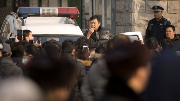 An official uses a loudspeaker on a Chinese police vehicle to speak to depositors from Ezubao outside the State Bureau for Letters and Calls Reception Division office in Beijing early last month. 
