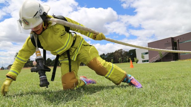 ACT Fire and Rescue firefighter Kari Harlovich drags a fire hose attached to a resistance cable today at the ACT Emergency Services Agency headquarters at Fairbairn.
