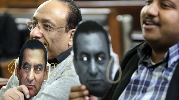 Supporters of Egypt's ousted President Hosni Mubarak hold masks with Mubarak's face during a session at the Cairo High Court in Egypt on Thursday. Mubarak is being retried over the killing of hundreds of protesters during the 2011 uprising that ended his nearly three decades in power.