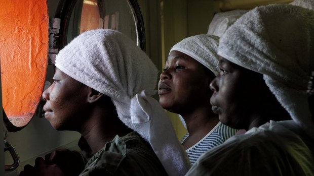Women look out through a porthole from aboard the Aquarius rescue vessel after arriving in Sicily on June 26. 