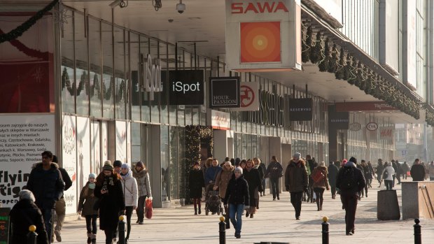 Pedestrians walk past retail stores at a shopping precinct in central Warsaw, Poland, one of the countries among complainants.