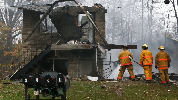 Firefighters work at the scene where authorities say a small business jet crashed into an apartment building.