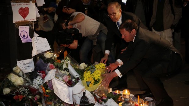 Australia's Energy Minister Josh Frydenberg, right, and Ambassador Stephen Brady place flowers at the Bataclan memorial in Paris on Monday.