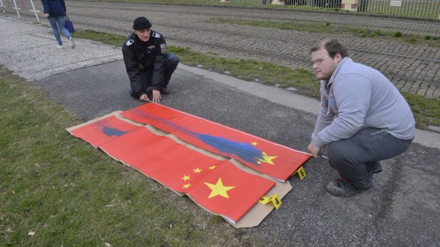 Policemen inspect Chinese flags defaced near Prague Castle on Saturday, ahead of the visit of Chinese President Xi Jinping.